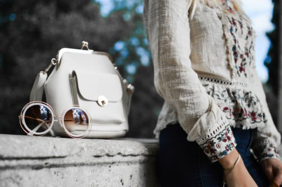 Purse and sunglasses next to a woman.